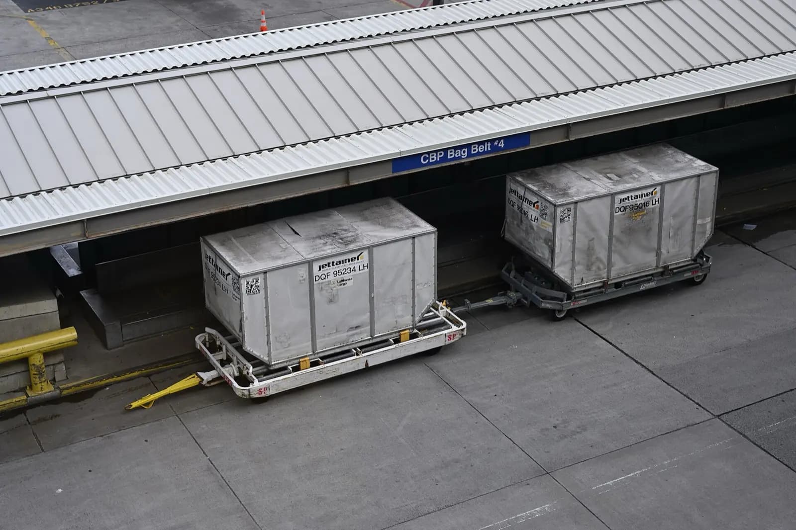 Air cargo containers on dollies beside an airport terminal